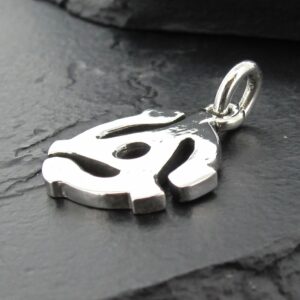 Close-up of a silver pendant with a unique abstract design on a dark surface.