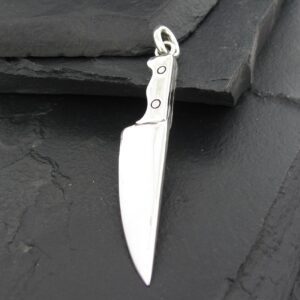 A silver knife pendant on a dark surface.