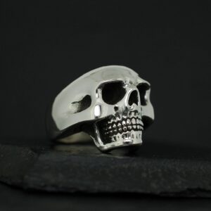 A detailed silver skull ring on a black background.