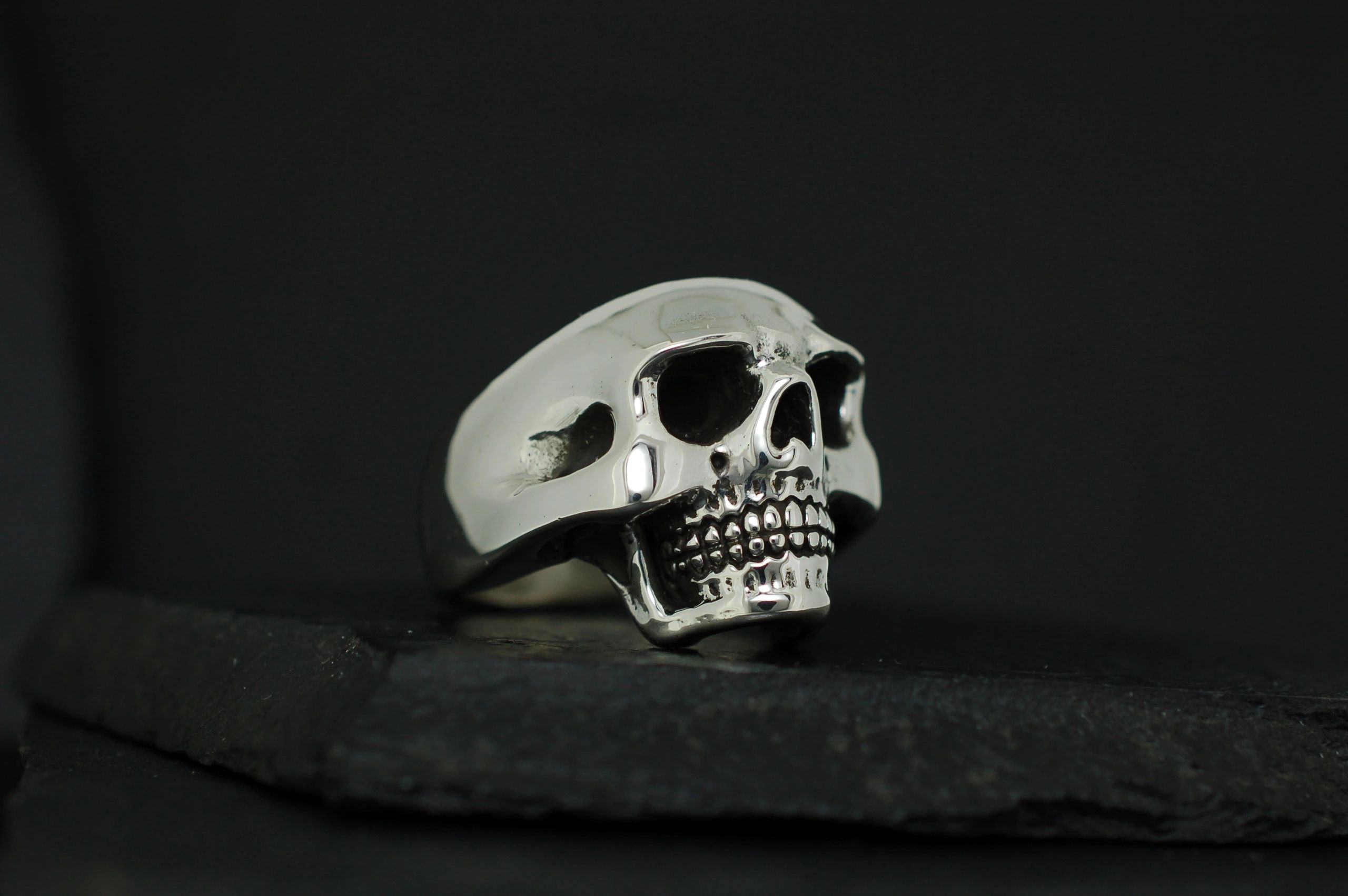 A detailed silver skull ring on a black background.