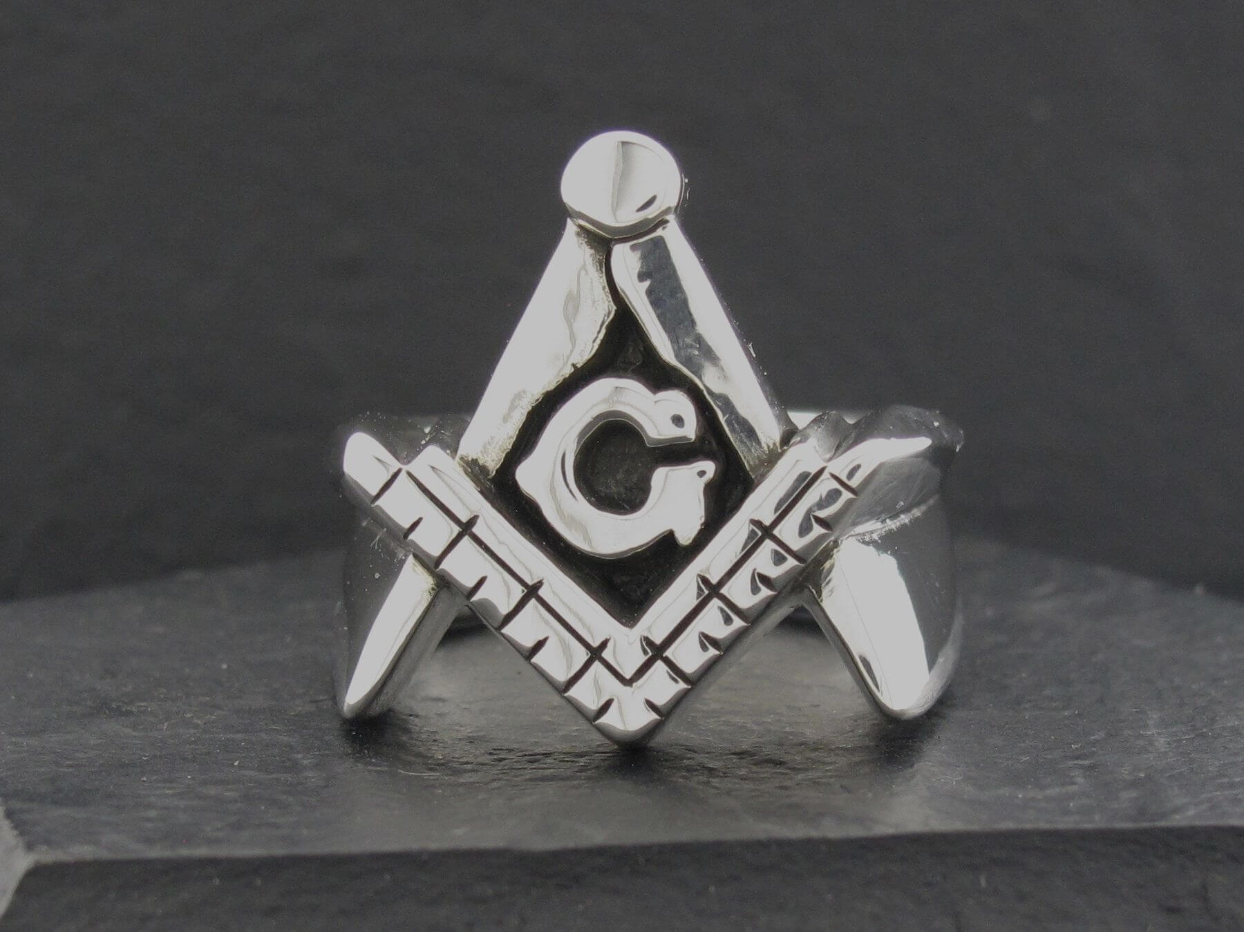 Silver Freemason symbol featuring a compass, square, and letter G.