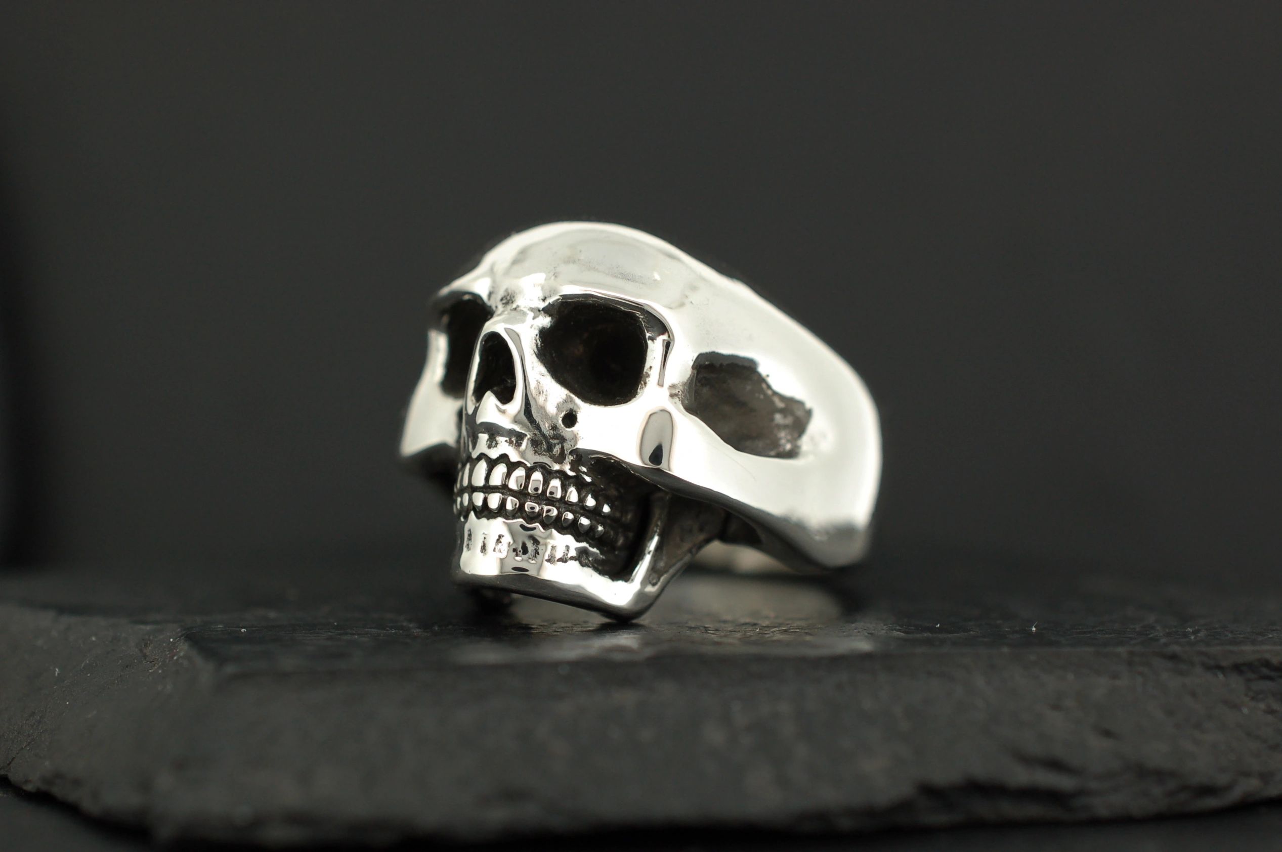 A silver skull ring with detailed teeth and hollow eyes.
