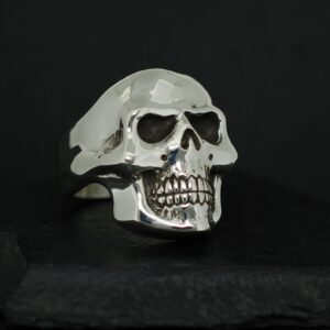 A silver skull-shaped ring with detailed teeth and eye sockets.
