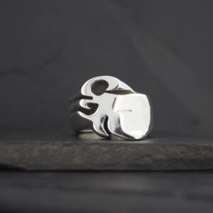Silver ring with a flame design on a dark surface.