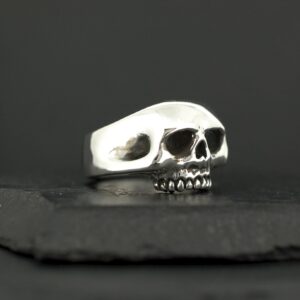 A silver skull-shaped ring on a dark surface.