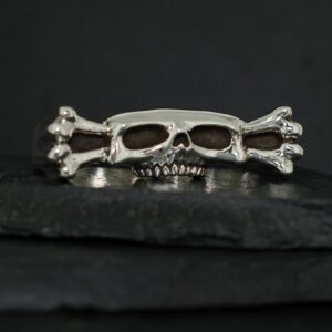 Silver skull and crossbones ring on a dark surface.