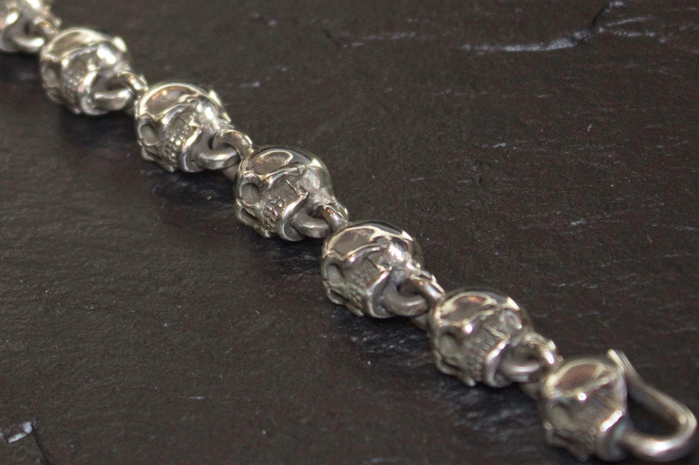 Close-up of a silver bracelet with intricately designed skull links.