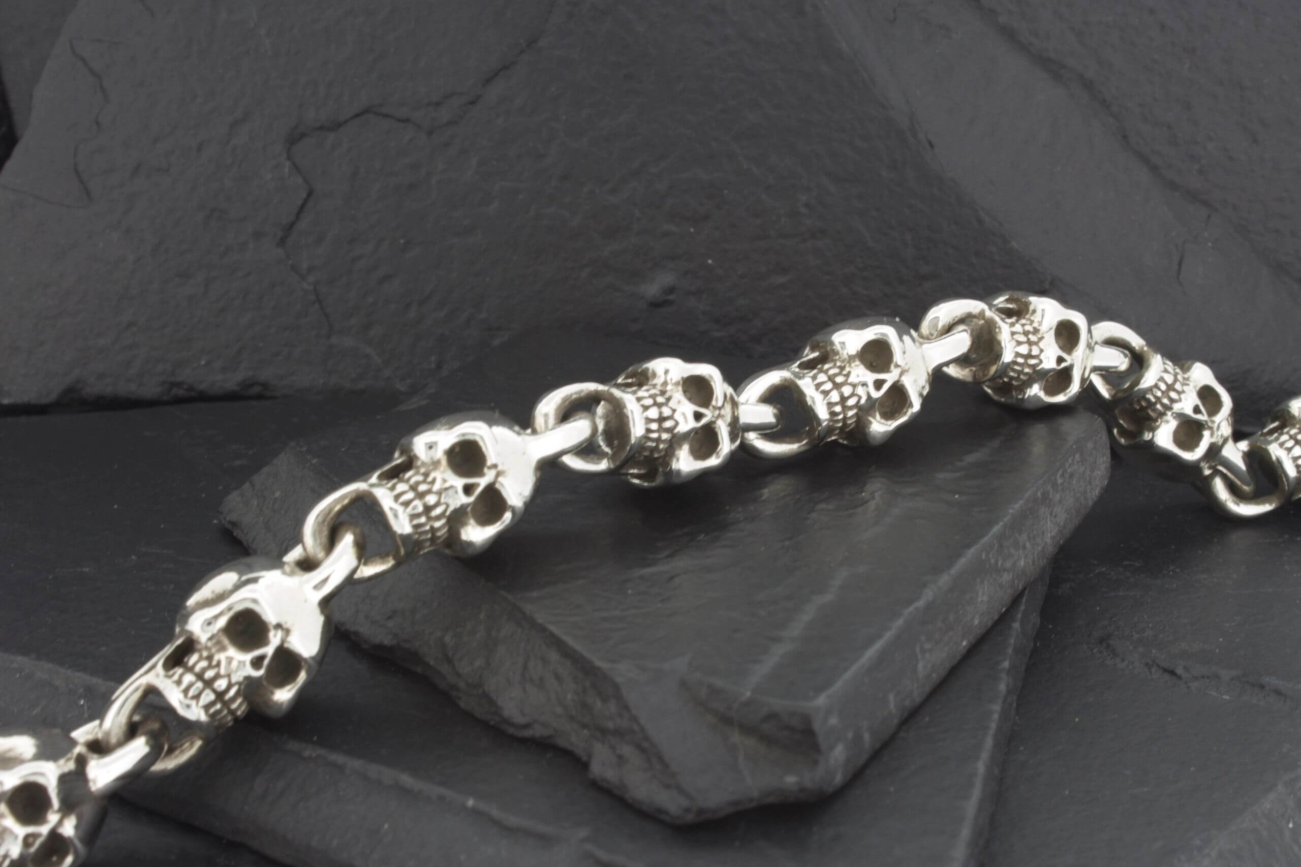 A silver bracelet made of interconnected skulls.