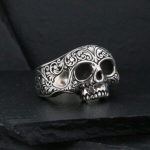 Ornate skull ring on dark slate surface.