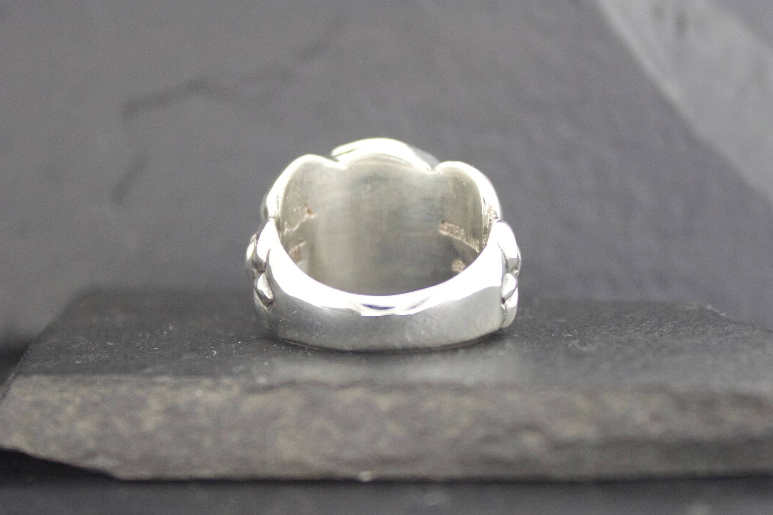 Close-up of a polished silver ring with a smooth, rounded design.