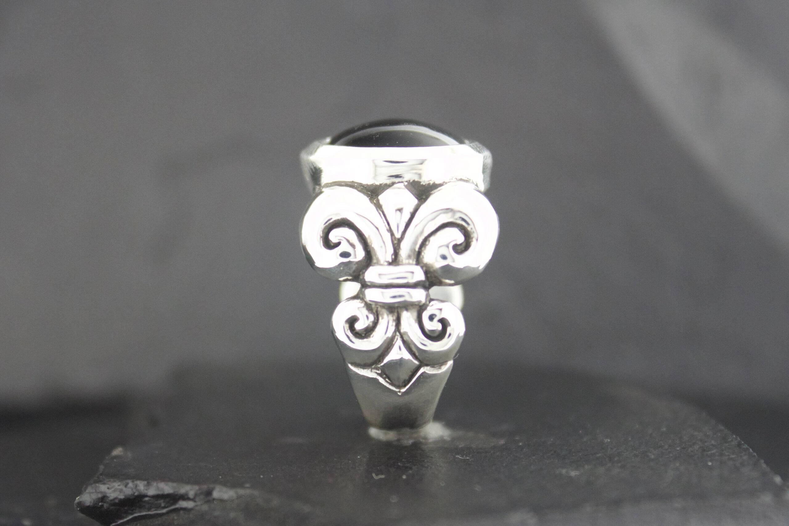 Close-up of a silver ring with intricate, ornamental design.