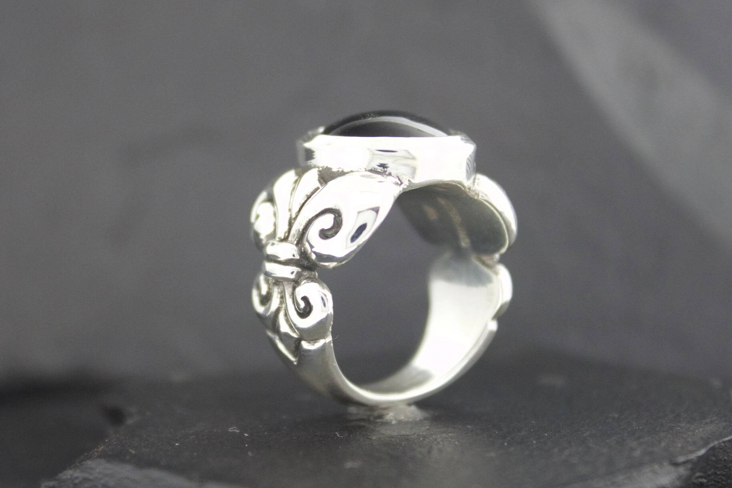 Silver ring with intricate butterfly design on black background.