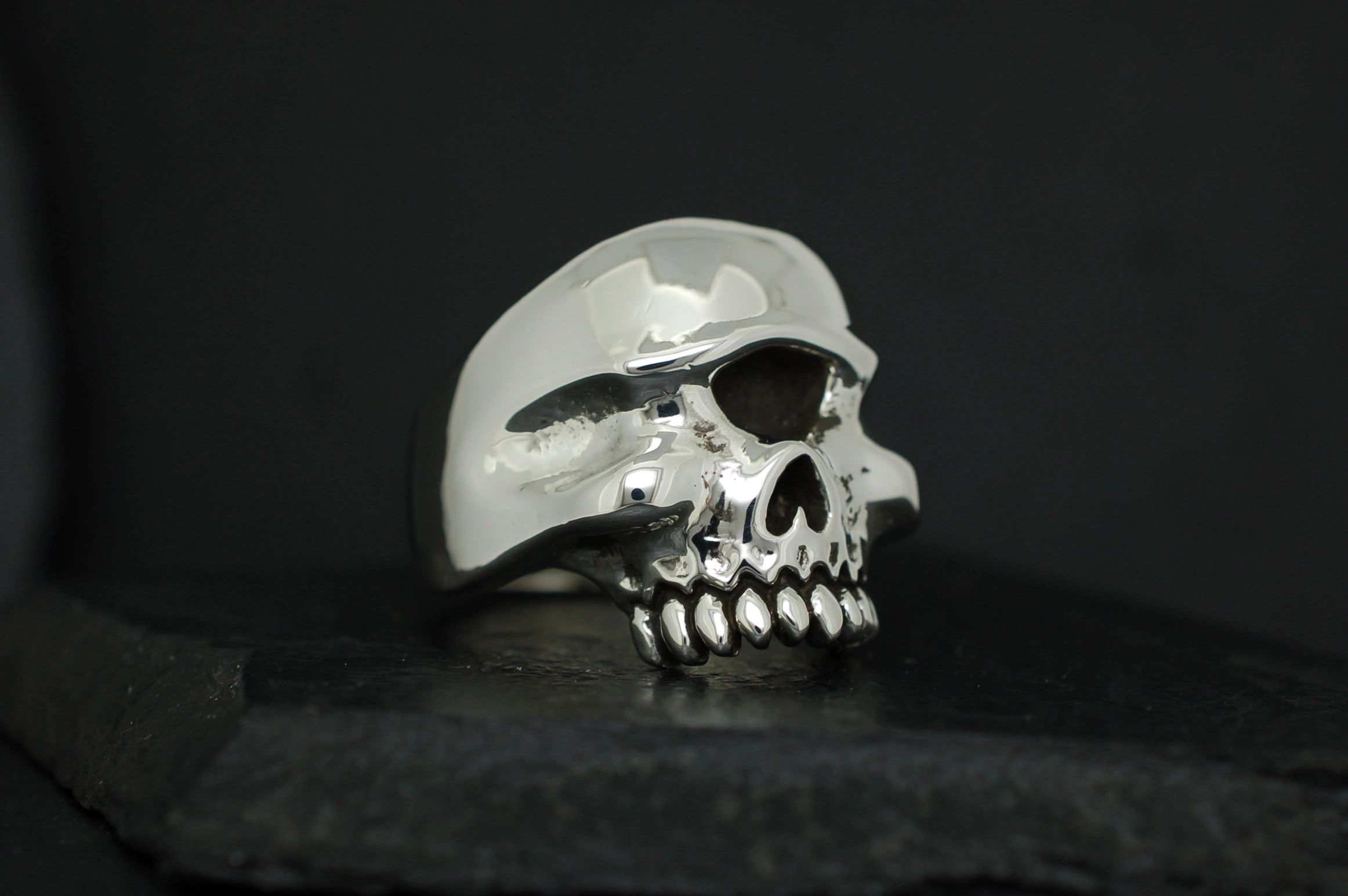A shiny silver skull sculpture on a dark background.