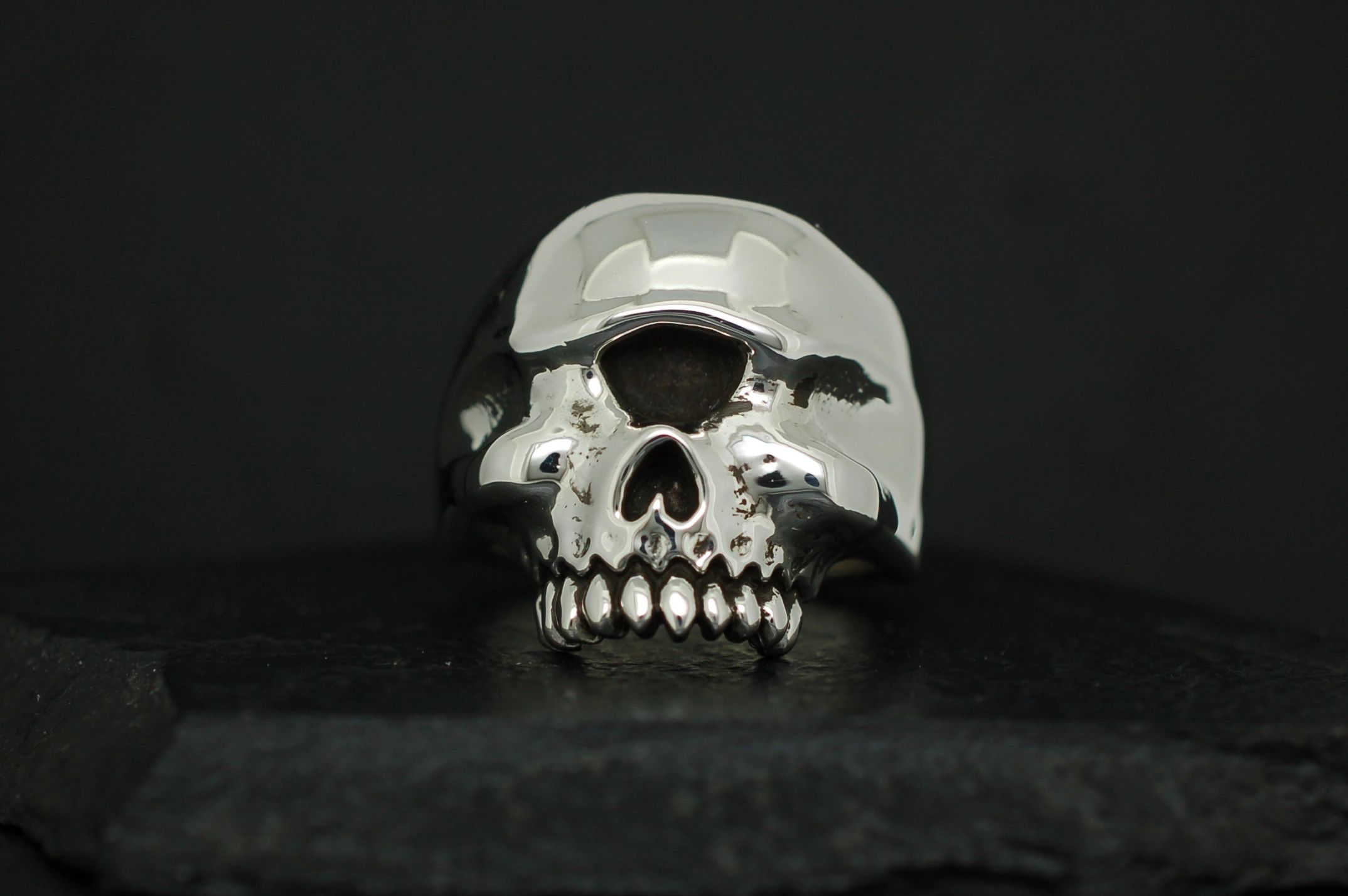 A shiny metallic skull sculpture on a dark background.