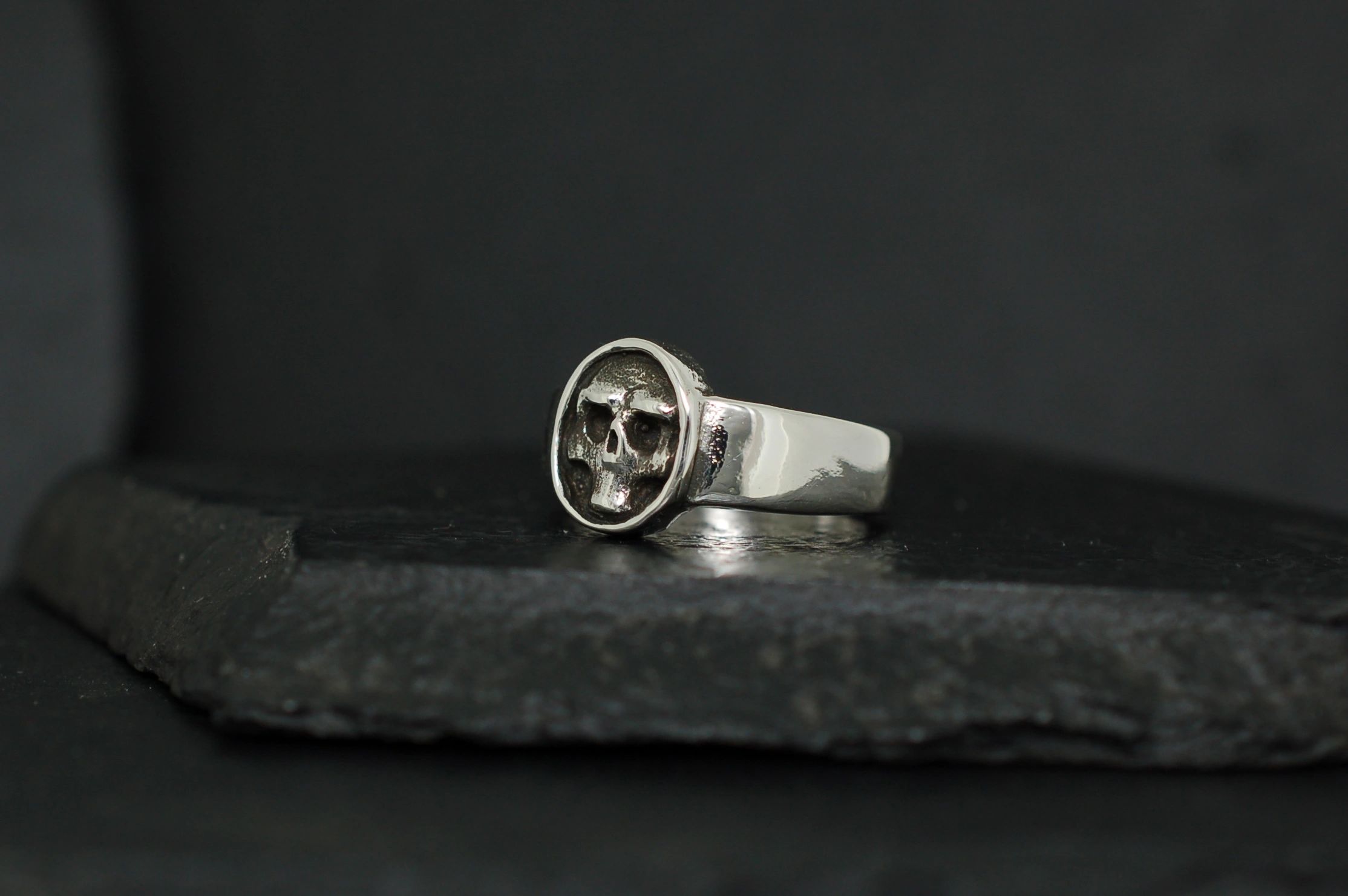 Silver ring with a compass design on a dark stone surface.