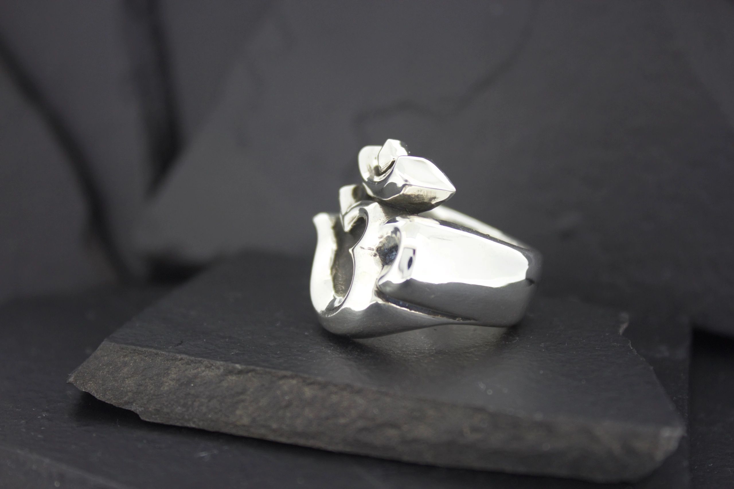 Close-up of a silver ring with a distinctive design on a dark surface.