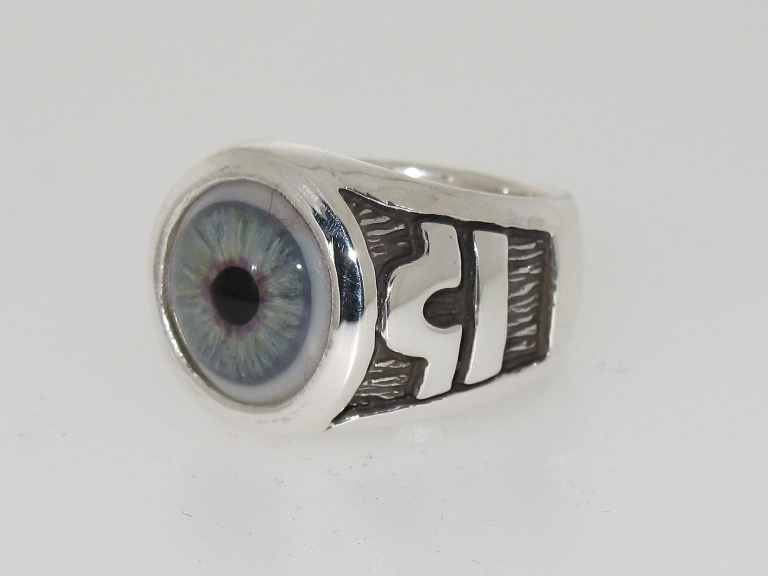 Silver ring with a detailed blue eye design on top.