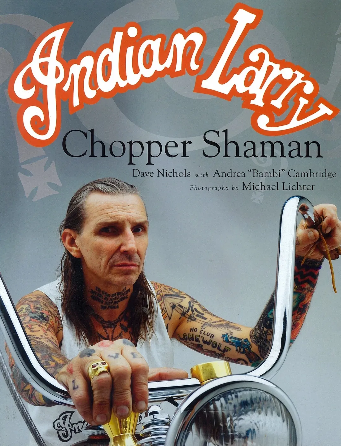 Profile of a tattooed man holding a knife on a chopper motorcycle.