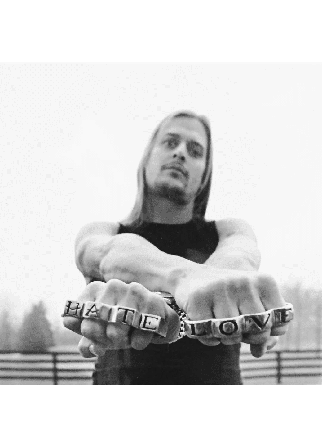 Man with long hair showing brass knuckles spelling 'LOVE'.