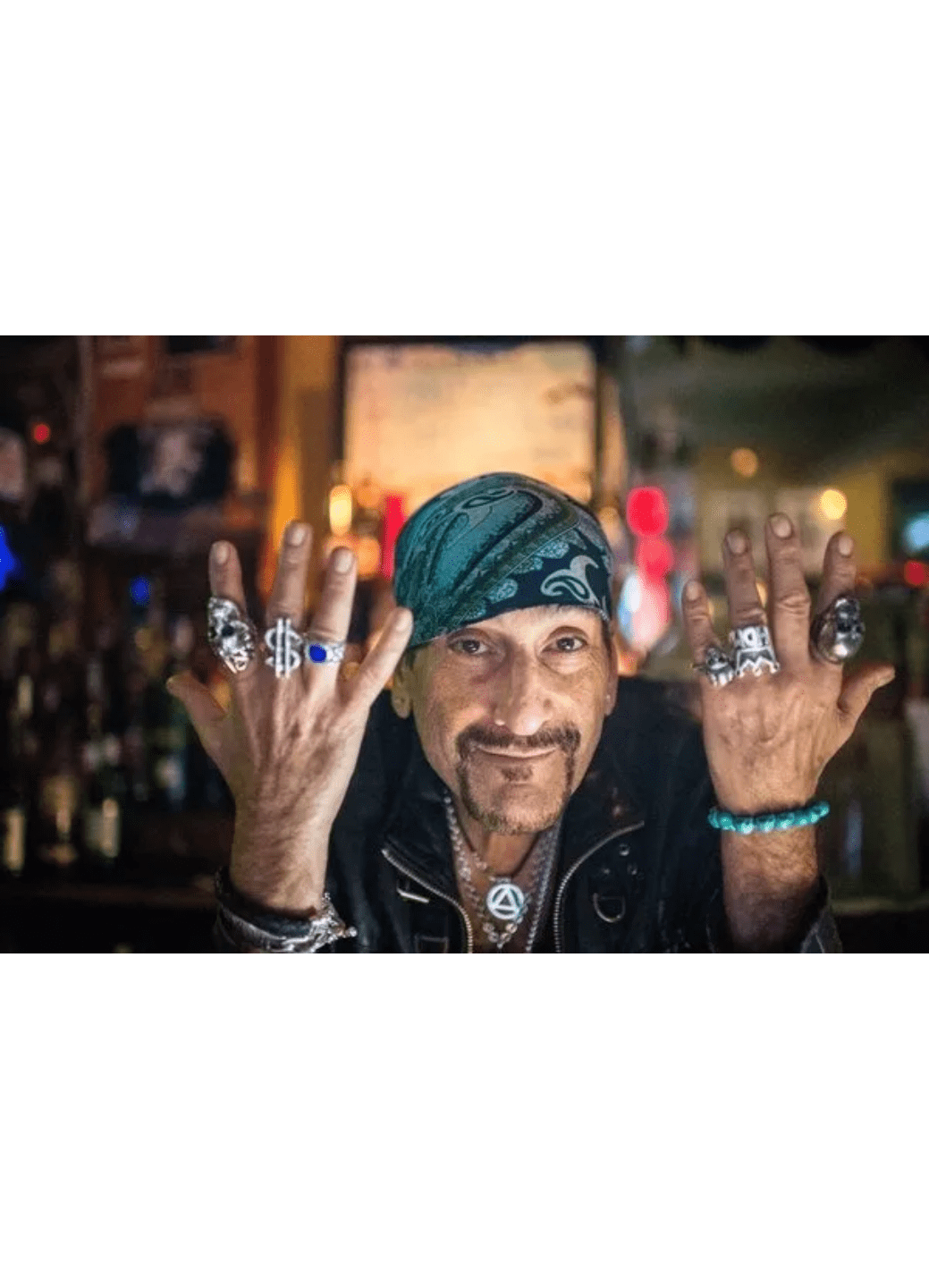 A man with a turban showing rings on his fingers in a cozy bar.