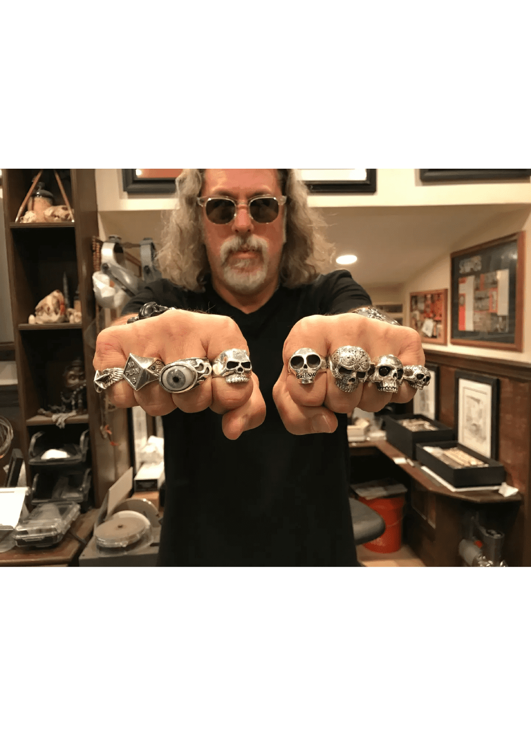 Man showing off multiple large rings on his fingers.