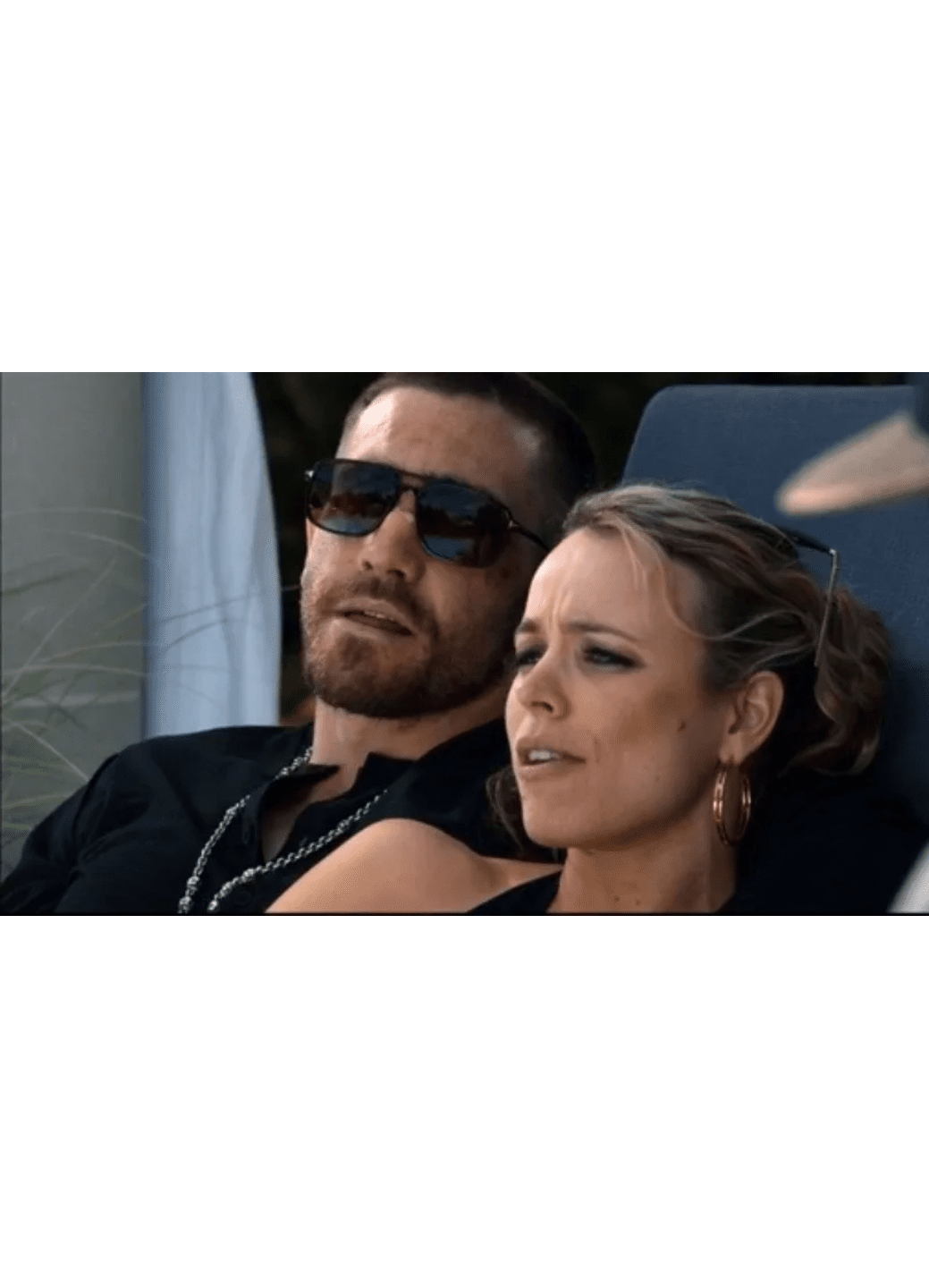 A man and woman sitting together, the man wearing sunglasses.