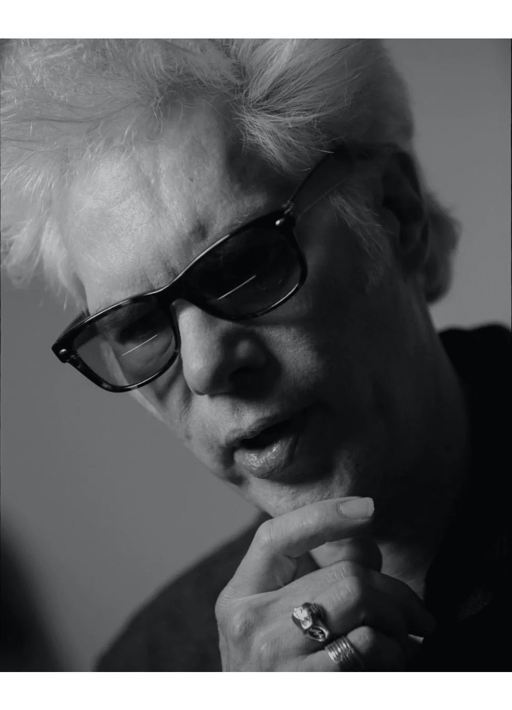 Black and white portrait of a man wearing sunglasses, deep in thought.
