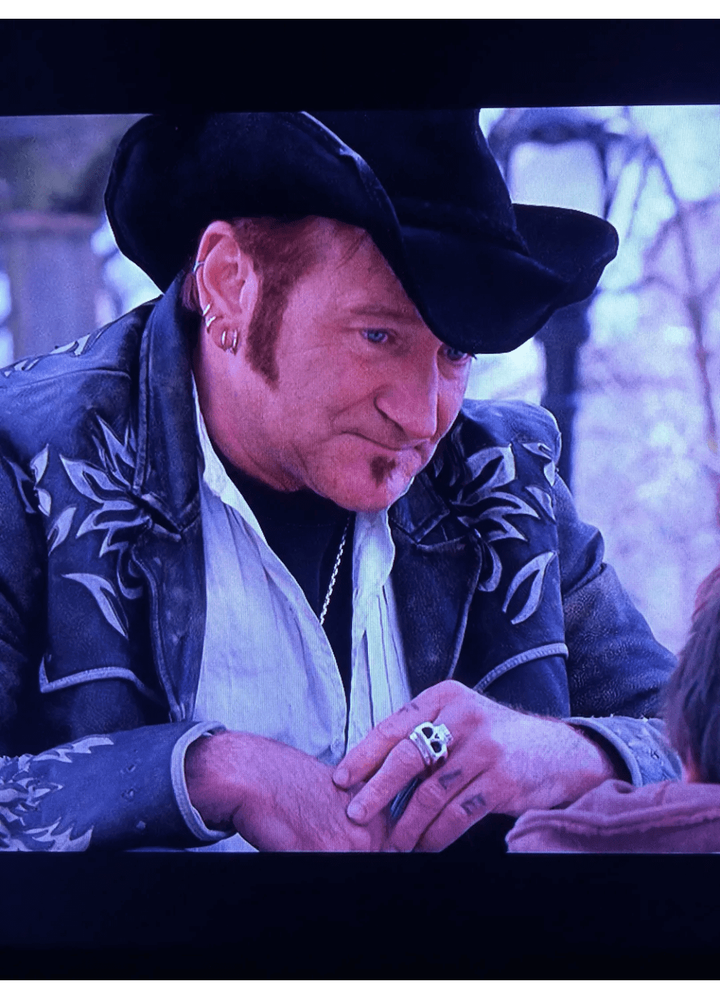 Man in a cowboy hat smiling and writing.