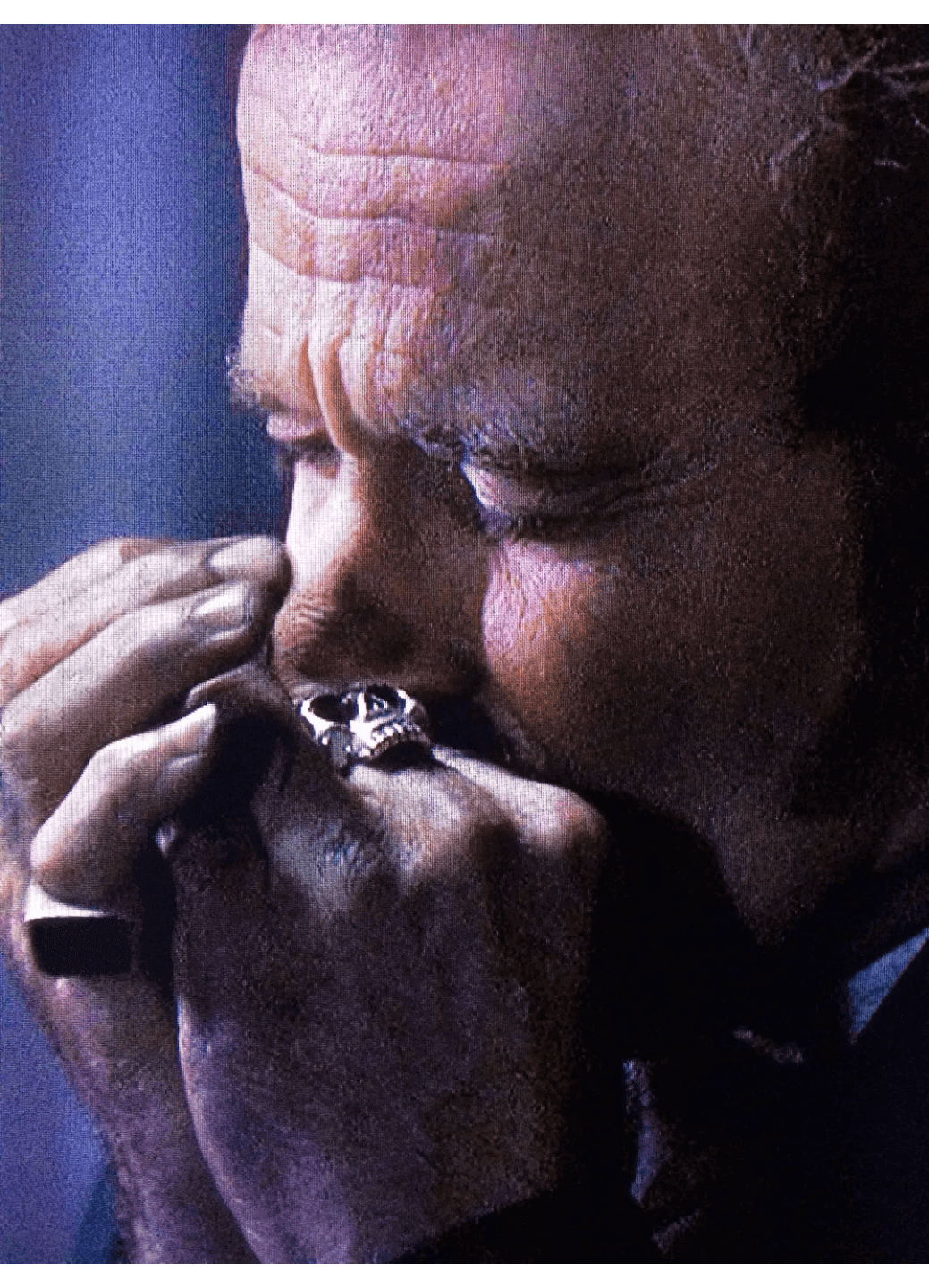 A man intensely playing a harmonica with closed eyes.