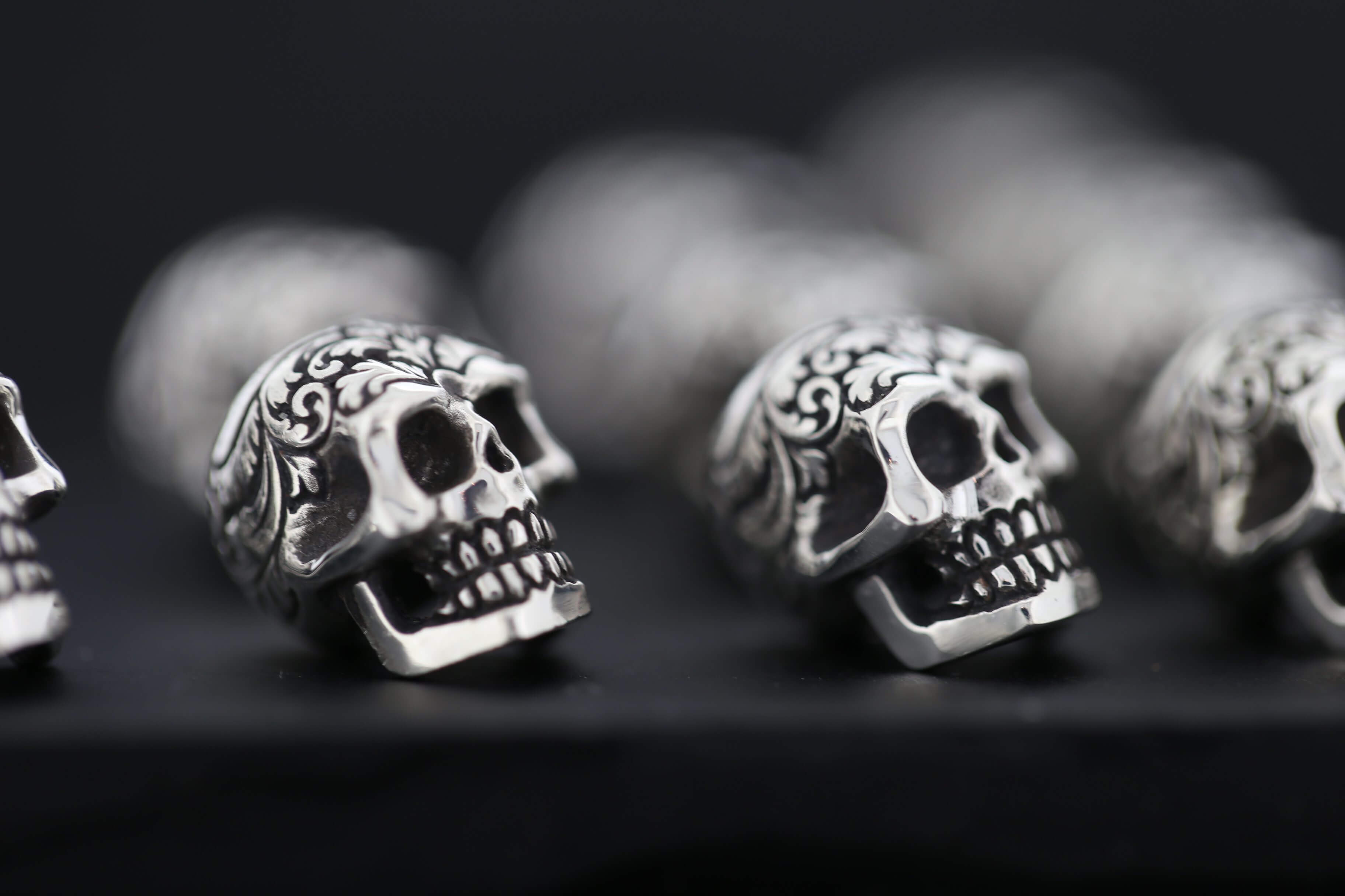 Ornate silver skulls in a row.
