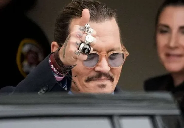 Man with sunglasses giving thumbs up gesture.