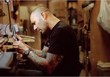 Tattooed man working in a workshop.